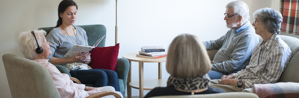 Kvinna läser till äldre personer från en bok